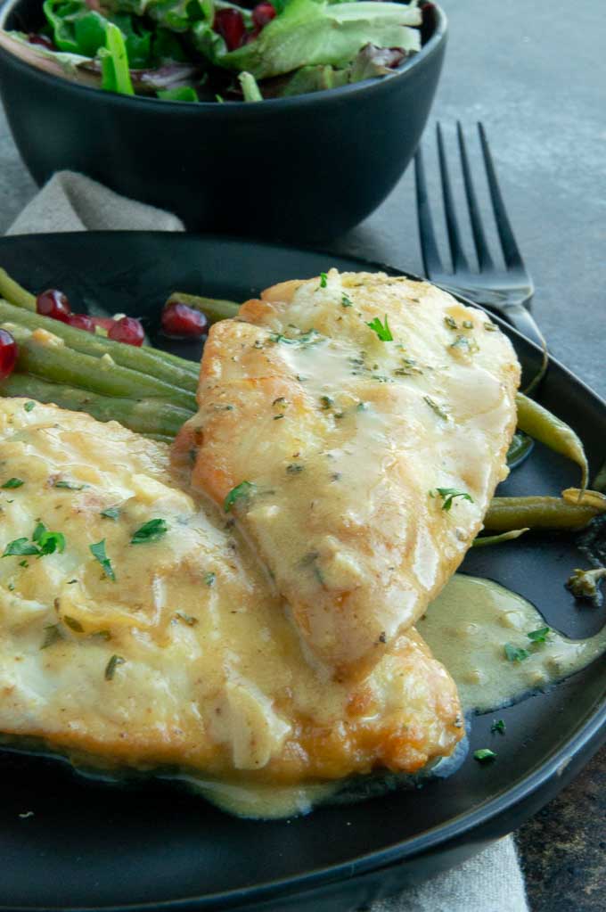 mustard chicken saute on a black plate with green beans