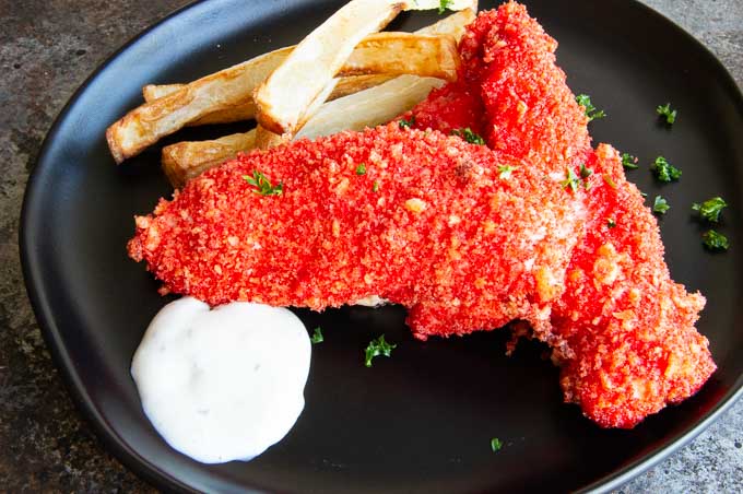 cheeto crusted chicken on a black plate