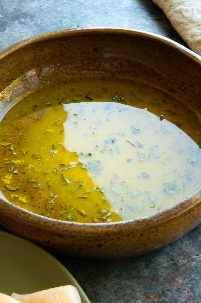 vinegar, oil and herbs in a brown bowl