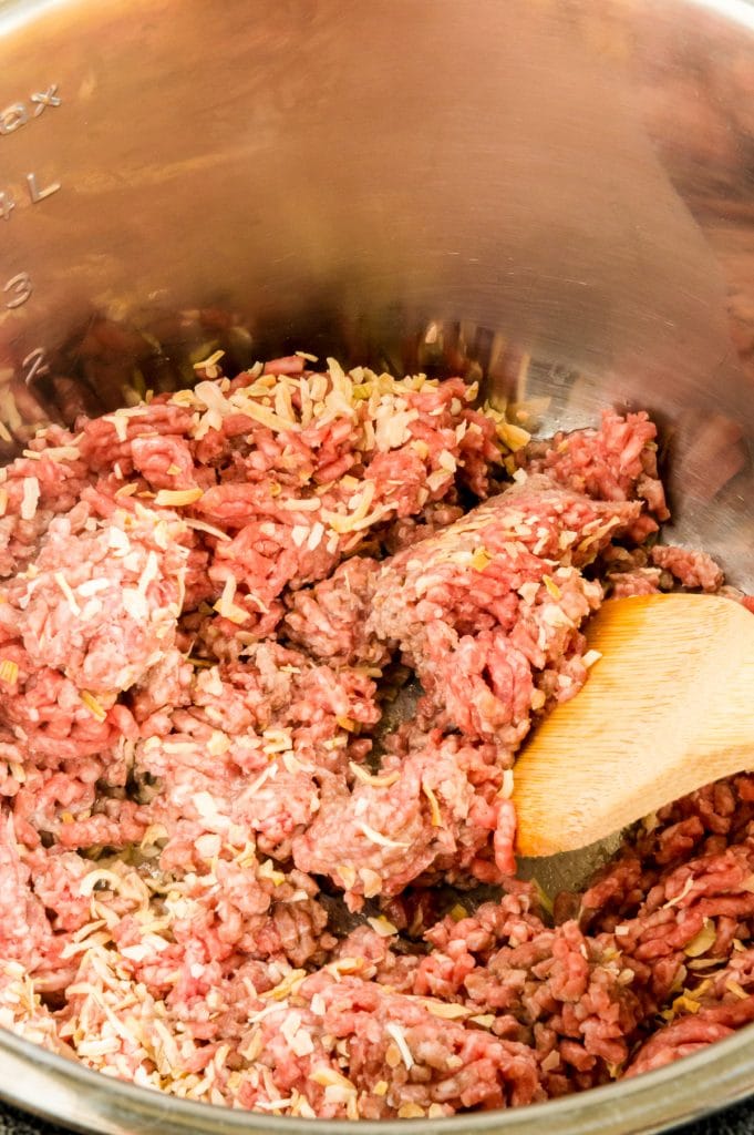 raw ground beef with onions being stirred