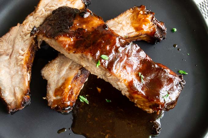 sticky sauce laden ribs on a black plate