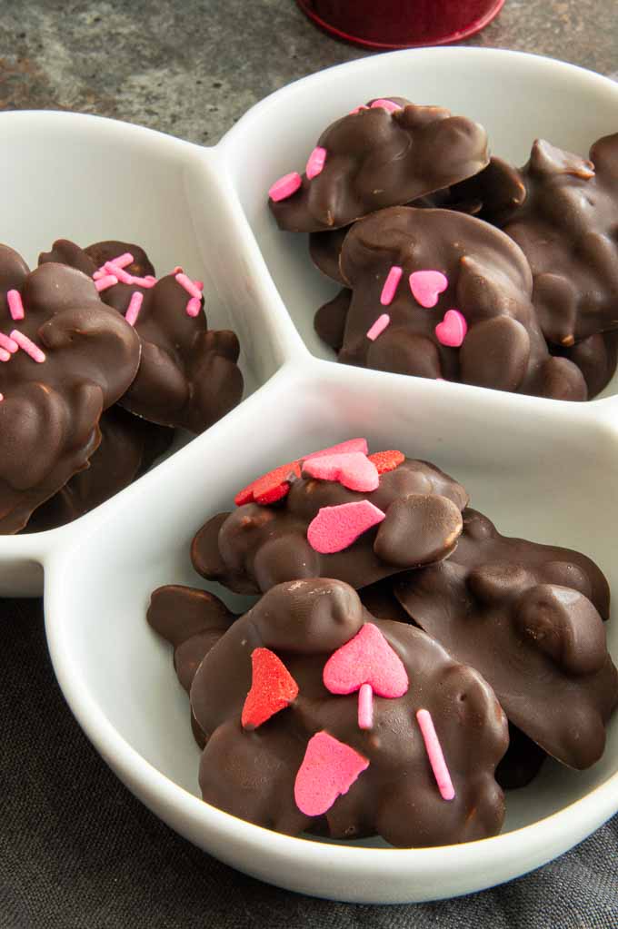Candy dish with peanut clusters with heart shaped sprinkles in it.
