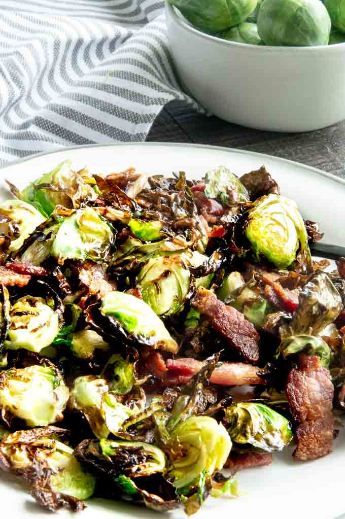 Brussel sprouts with bacon on a white plate with a bacon fat glaze