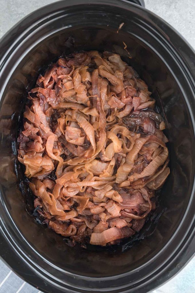 slow cooker base filled with browned caramelized onions after cooking for 10 hours