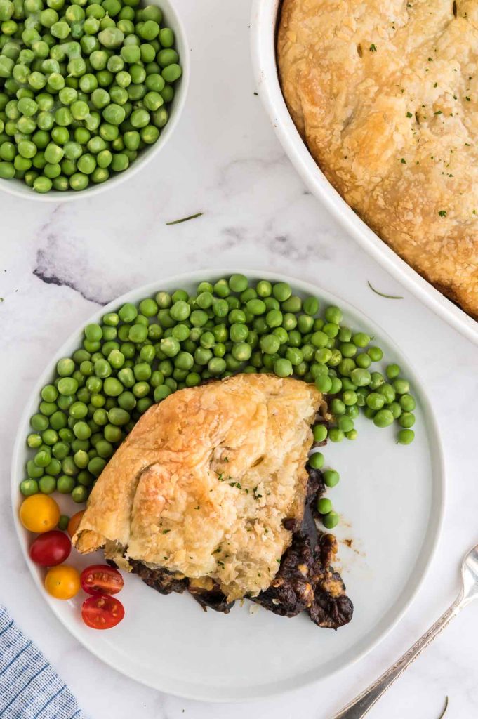 tabletop serving of guinnes pie and a bowl of peas