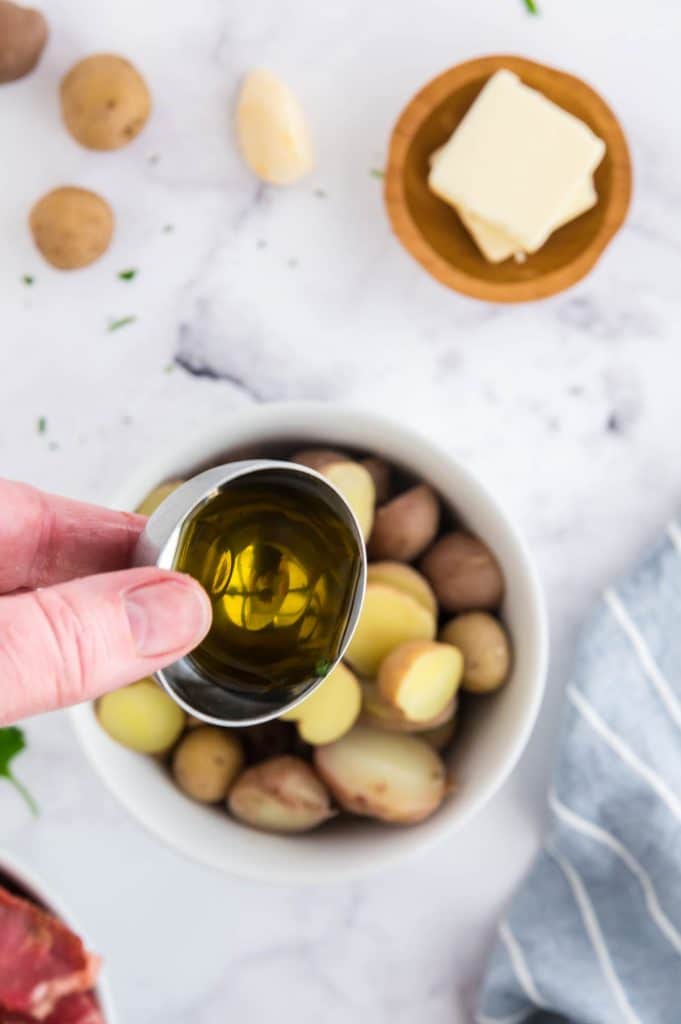 tossing potatoes in olive oil before cooking