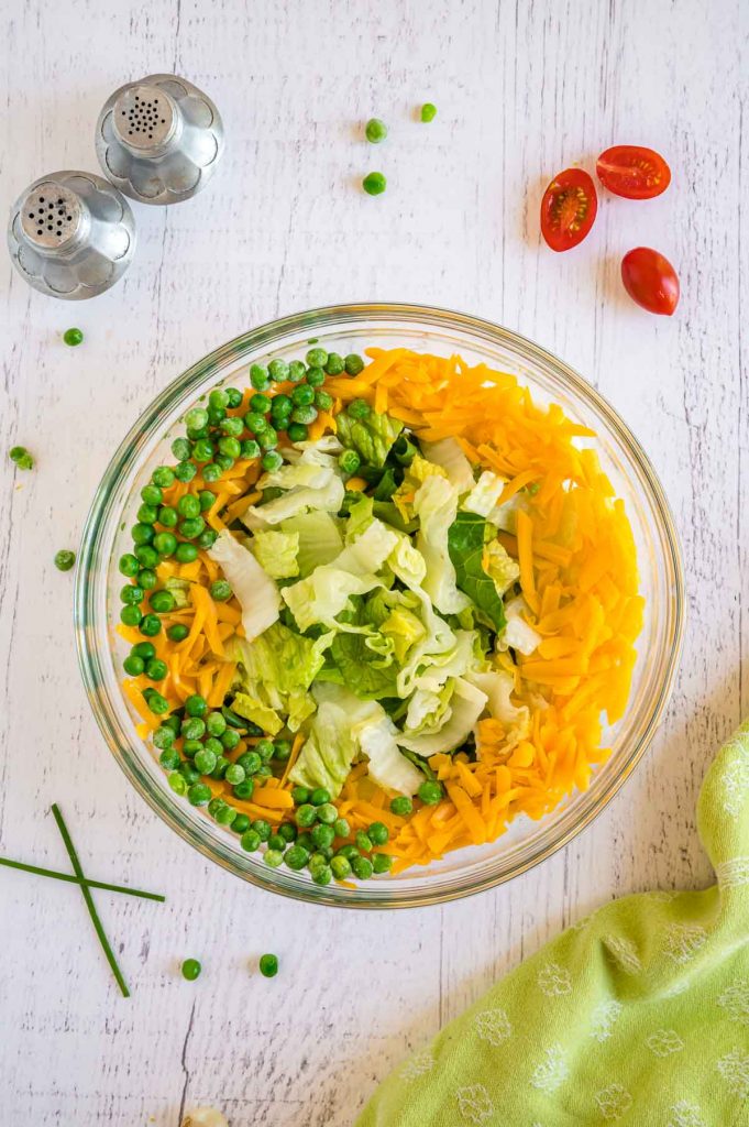 layering the salad with peas and cheese