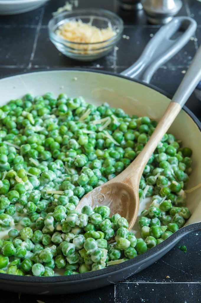 Scooping out honey butter peas from the skillet
