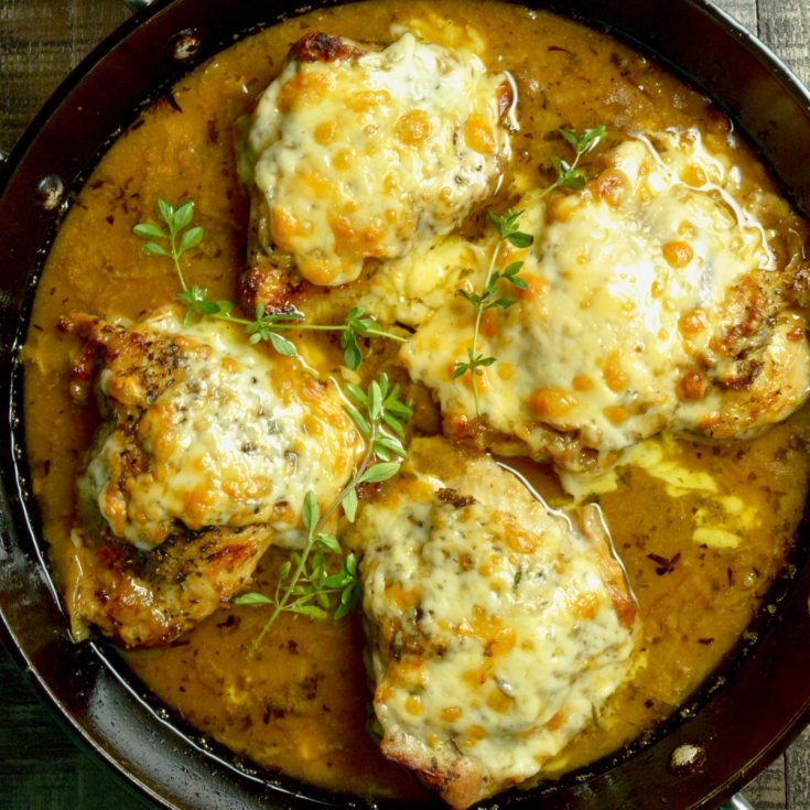 Melted cheese over French onion chicken in a pan