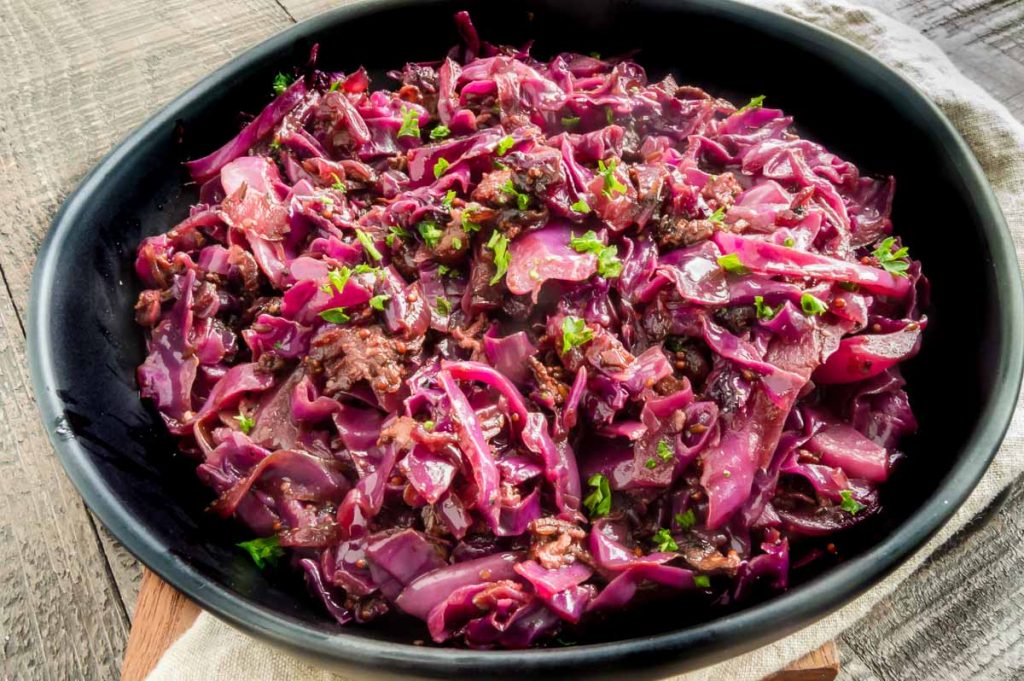 black bowl with red cabbage in it alone on a table